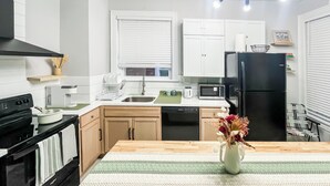 A modern kitchen with white cabinets, a black refrigerator, a microwave, and a stove. - Exqusite Emerald (St. Louis)