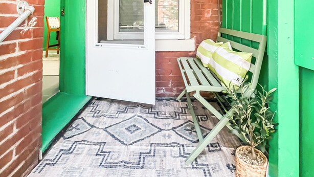 A green-walled room with a wooden bench, a potted plant, and a window with a white frame. - Exqusite Emerald (St. Louis)