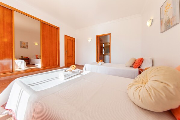 A hotel room with two beds, a large mirror, and a wooden wardrobe. - Villa Peace (Silves)