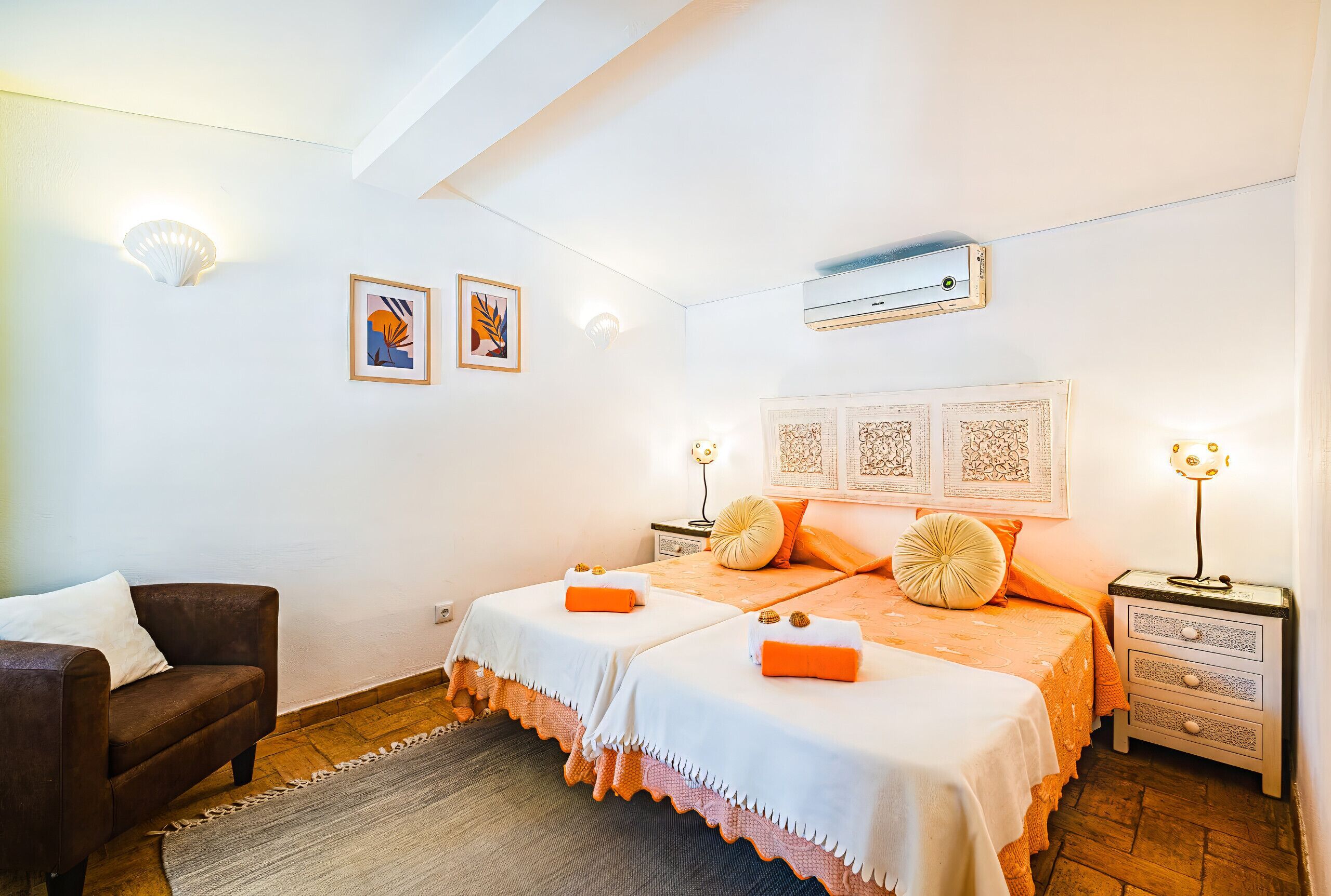 A bedroom with two beds, a sofa, a nightstand, and wall-mounted artwork.