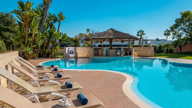A poolside area with lounge chairs and a small pavilion. - Apartment Niya (Loulé)