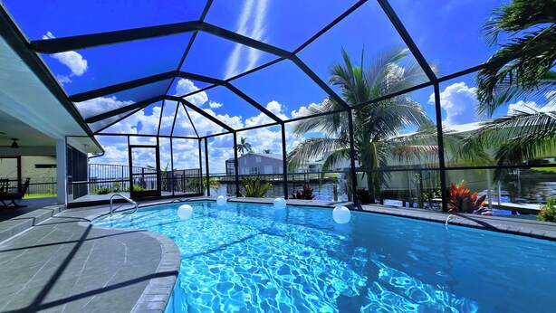 Una piscina amb aigua turquesa cristal·lina, envoltada d'una zona coberta amb una estructura metàl·lica geomètrica.