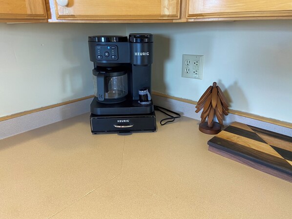 A Keurig coffee maker on a kitchen counter with wooden cabinets above.