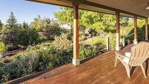 A wooden deck with a table and chairs, overlooking a garden with various plants and trees. - Charming farmhouse in Historic Spring City with AC, WiFi, and full kitchen. (Spring City)