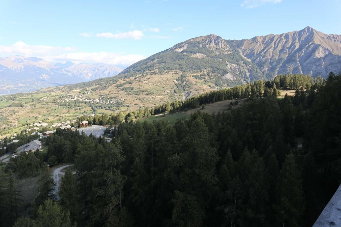 A mountainous landscape with a village and dense forest.
