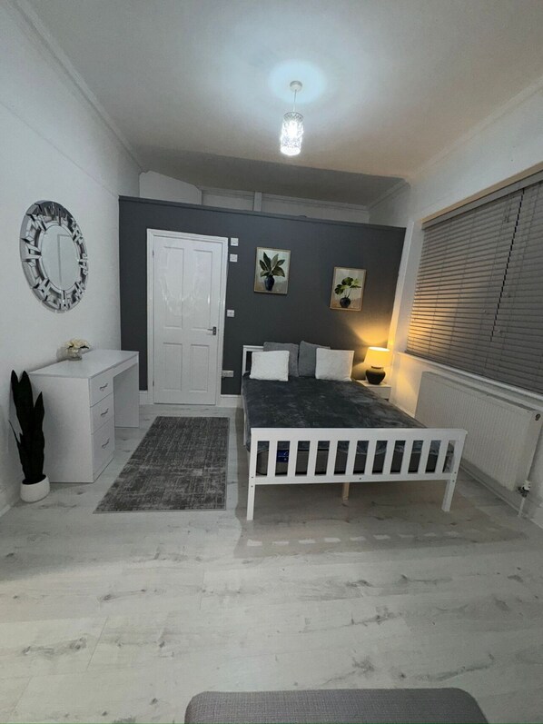 Un dormitorio con cama, cómoda, espejo y puerta.