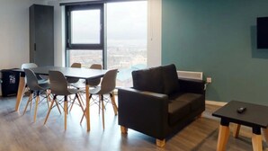 A modern living room with a dining area, large windows, and a view of the city. - For Students Only Canvas Arundel House in Coventry (Coventry)