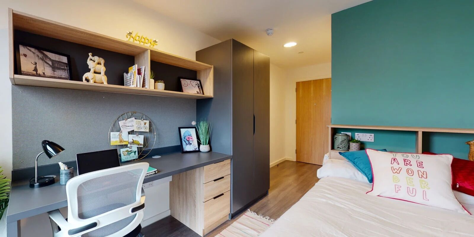 A modern bedroom with a desk, a bed, and a wardrobe.