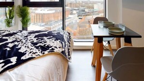 A bedroom with a large window, a bed, a dining table with chairs, and a TV on the wall. - For Students Only Canvas Arundel House in Coventry (Coventry)
