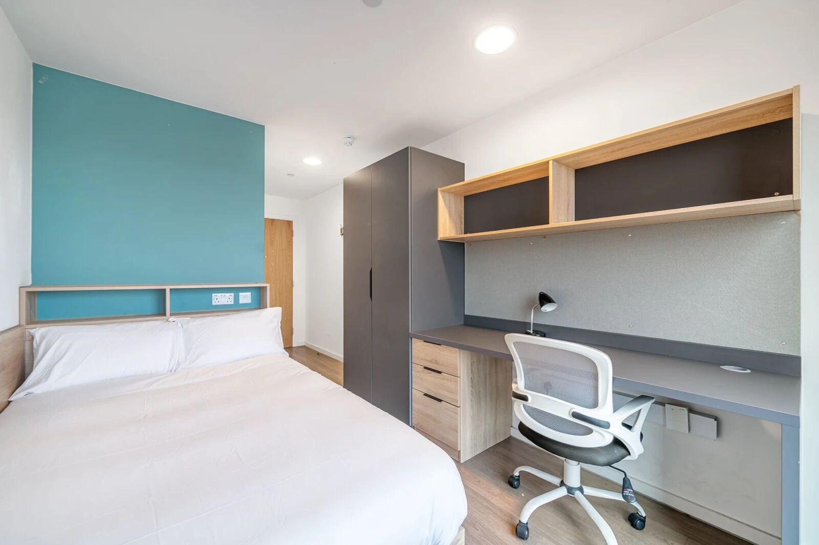 A modern bedroom with a bed, a desk, and a chair.