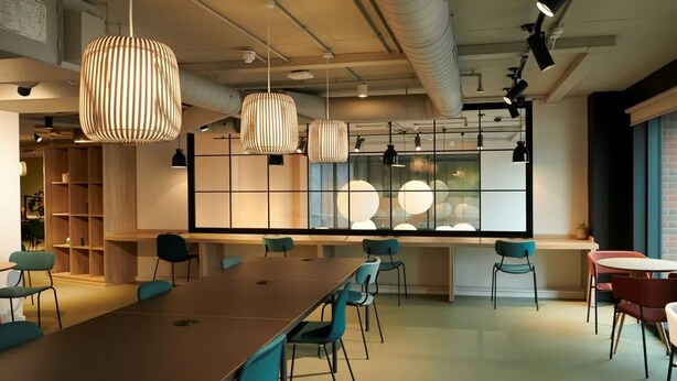 A modern meeting room with a long table, teal chairs, pendant lighting, and a large window with a view. - For Students Only Canvas Arundel House in Coventry (Coventry)