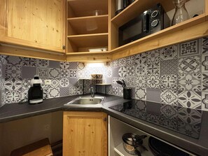 A kitchen with a black countertop, a sink, and patterned backsplash tiles.