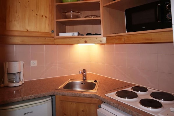 A kitchen with a sink, stove, and microwave.