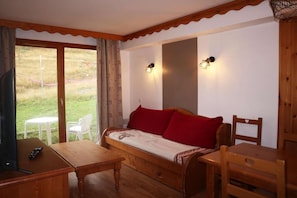 A cozy room with a wooden sofa, a small table, and a TV.