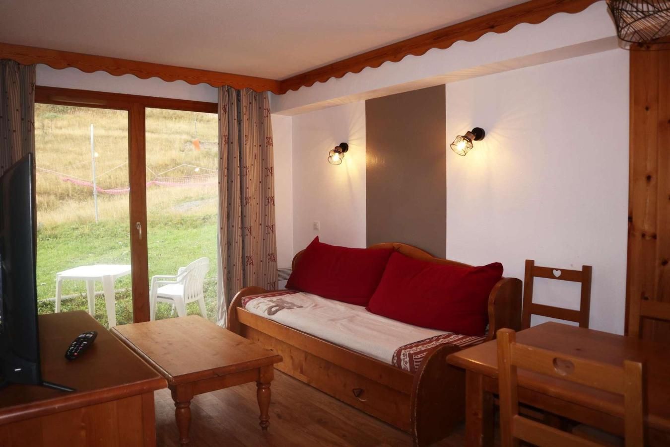 A cozy room with a wooden sofa, a small table, and a TV.