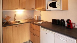 A compact kitchen with wooden cabinets, a microwave, a toaster, a coffee maker, and a dishwasher. - Resort center, 3rd floor, balcony, tv, ski locker, 28m², Les Orres (Les Orres)