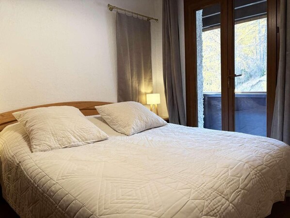 Un lit bien fait, avec une couverture matelassée, deux oreillers et une lampe de chevet.