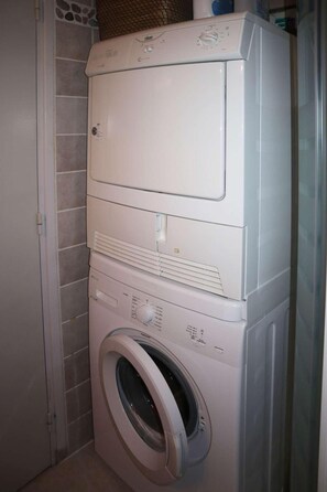 A stacked washer and dryer unit in a bathroom with tiled walls.