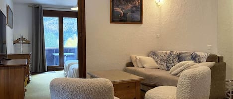A cozy living room with a sofa, two armchairs, a wooden coffee table, and a painting on the wall.