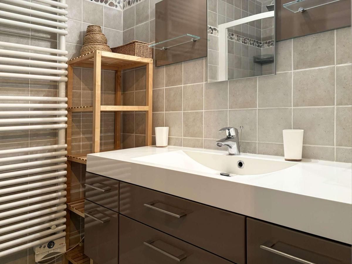 Ein modernes Badezimmer mit einem großen Waschbecken, zwei Spiegeln und einer Holzablage mit Körben.