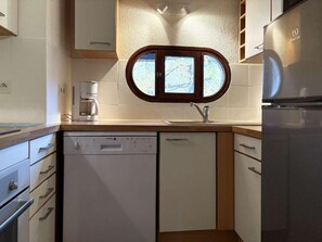 A compact kitchen with a dishwasher, a coffee maker, and a refrigerator.