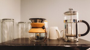 Eine Kaffeemaschine und eine Glaskaraffe auf einem dunklen Holztisch.