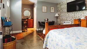 Ein Hotelzimmer mit einem Bett, einem Fernseher, einem Essbereich mit Stühlen und einem Tisch sowie einer Küchenzeile mit einem Herd und Stühlen.