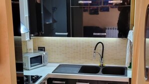 A compact kitchen with a microwave, stove, and sink. - Two-room apartament in heart of tuscany (Montopoli)
