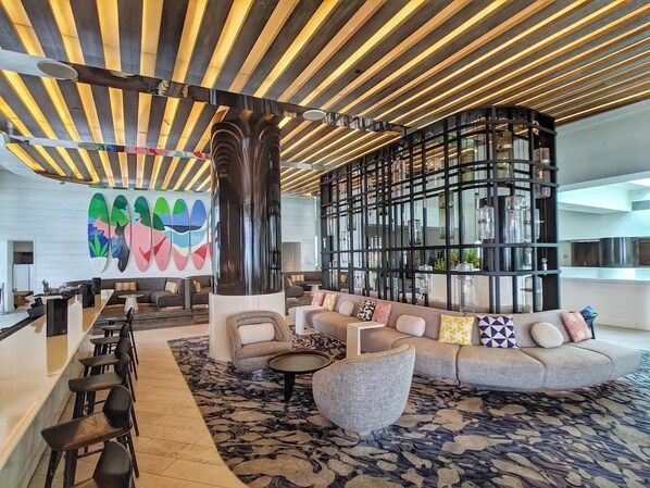 A modern lobby with a curved seating area, a large abstract mural, and a unique ceiling design.