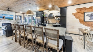 A modern kitchen with wooden ceiling, black cabinets, and a central island with bar stools. - 22 Guests | Luxury Chalet | Indoor Pool | Mtn View (Sevierville)