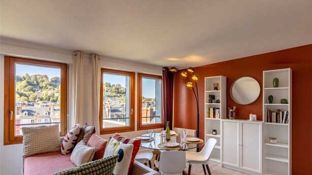 Una sala de estar moderna con comedor, ventanas amplias y vista a una colina.