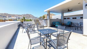 A rooftop terrace with outdoor seating, a pool, and a view of the city and mountains. - Maia Cabo by Naya Homes (Cabo San Lucas)