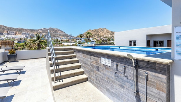 A rooftop pool area with a view of a cityscape and mountains in the background. - Maia Cabo by Naya Homes (Cabo San Lucas)
