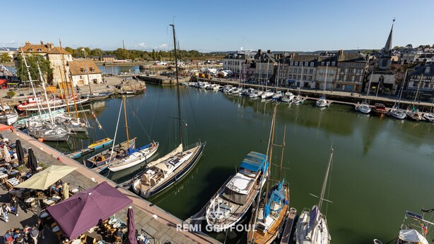 Een jachthaven met aangemeerde boten, een café aan het water en gebouwen met historische architectuur.