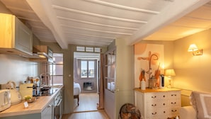 A compact kitchen with modern appliances, a dining area with a table and chairs, and a cozy sitting area with a lamp and decorative items. - Dolphin View - 2nd floor - Beautiful flat with view of the port (Honfleur)