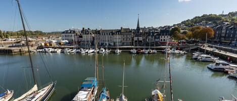 A marina with various boats docked, a prominent church with a tall spire, and a town with buildings in the background.