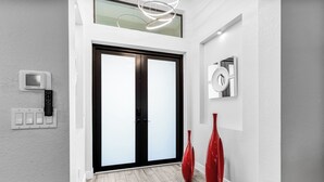 Un pasillo moderno con un par de puertas, un termostato y dos jarrones rojos.
