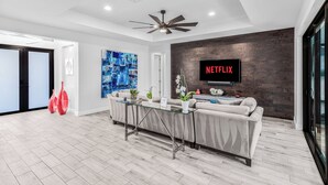 Una sala de estar moderna con un conjunto de sofás, una mesa de centro de vidrio y un televisor montado en una pared de madera.
