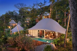 Un resort apartado con bungalows sobre el agua, piscina y exuberante vegetación.