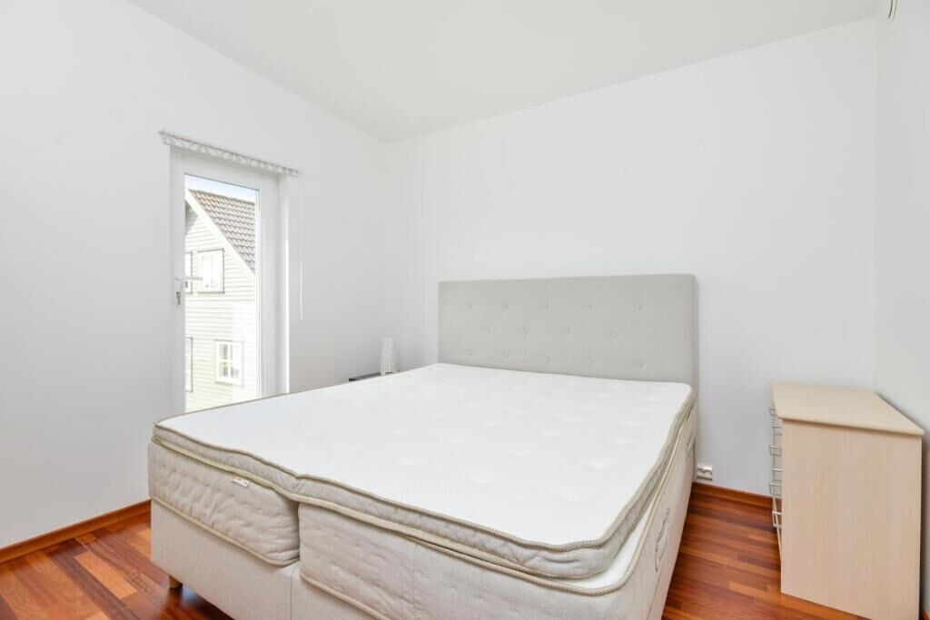 Une chambre à coucher avec un lit, une petite armoire et une fenêtre.