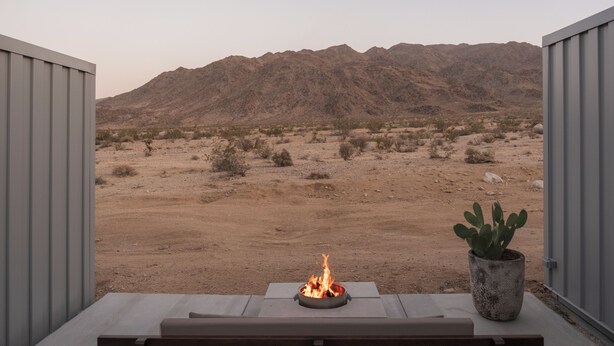 Un patio con una focolare, un cactus e vista su un paesaggio desertico con montagne.