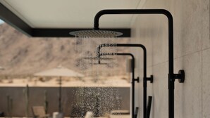 Una doccetta moderna con acqua corrente, una piscina e una sedia sullo sfondo.