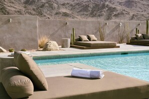 A poolside lounge area with cushioned seating and a towel. - RESET Hotel Joshua Tree National Park, Outdoor Collection by Marriott Bonvoy (Twentynine Palms)
