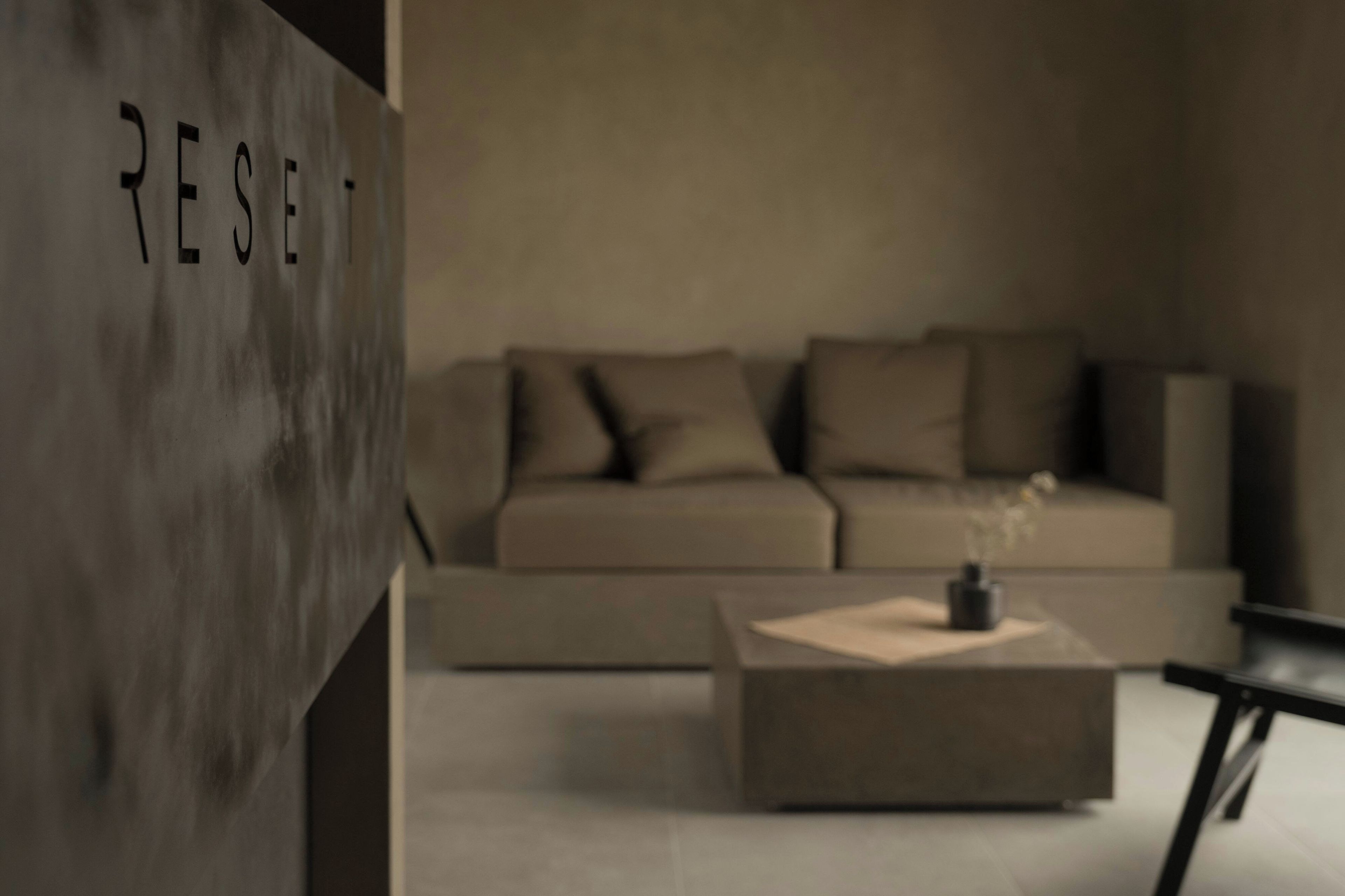 A modern living room with a sofa, a coffee table, and a wall with the word 'RESET' visible.