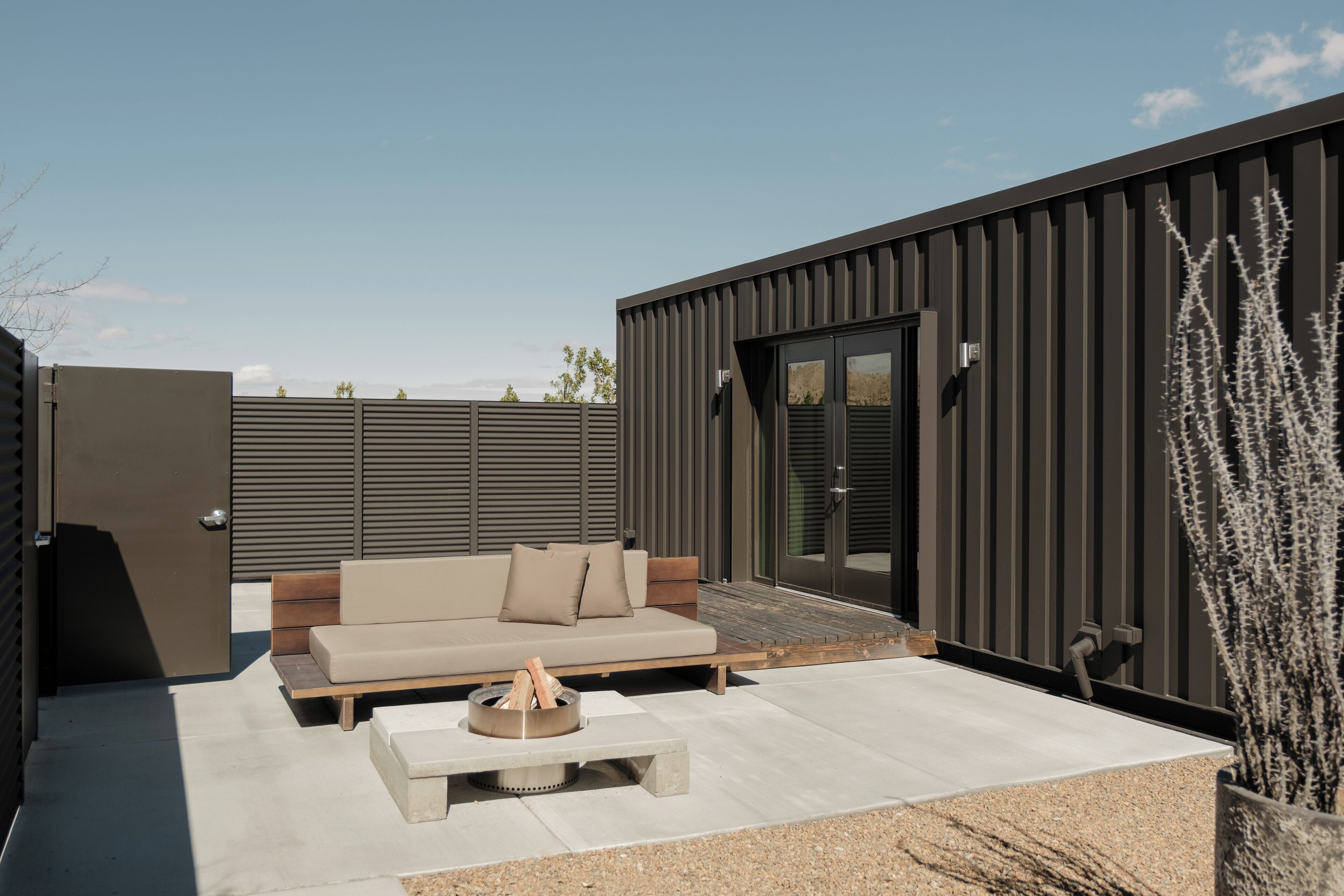 A modern outdoor living area with a sofa, a fire pit, and a patio table.