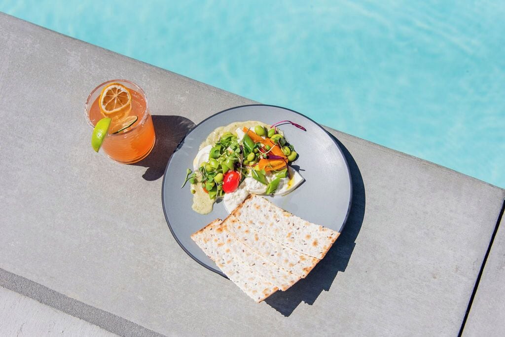 Un repas avec une boisson et du pain plat, servi au bord de la piscine.