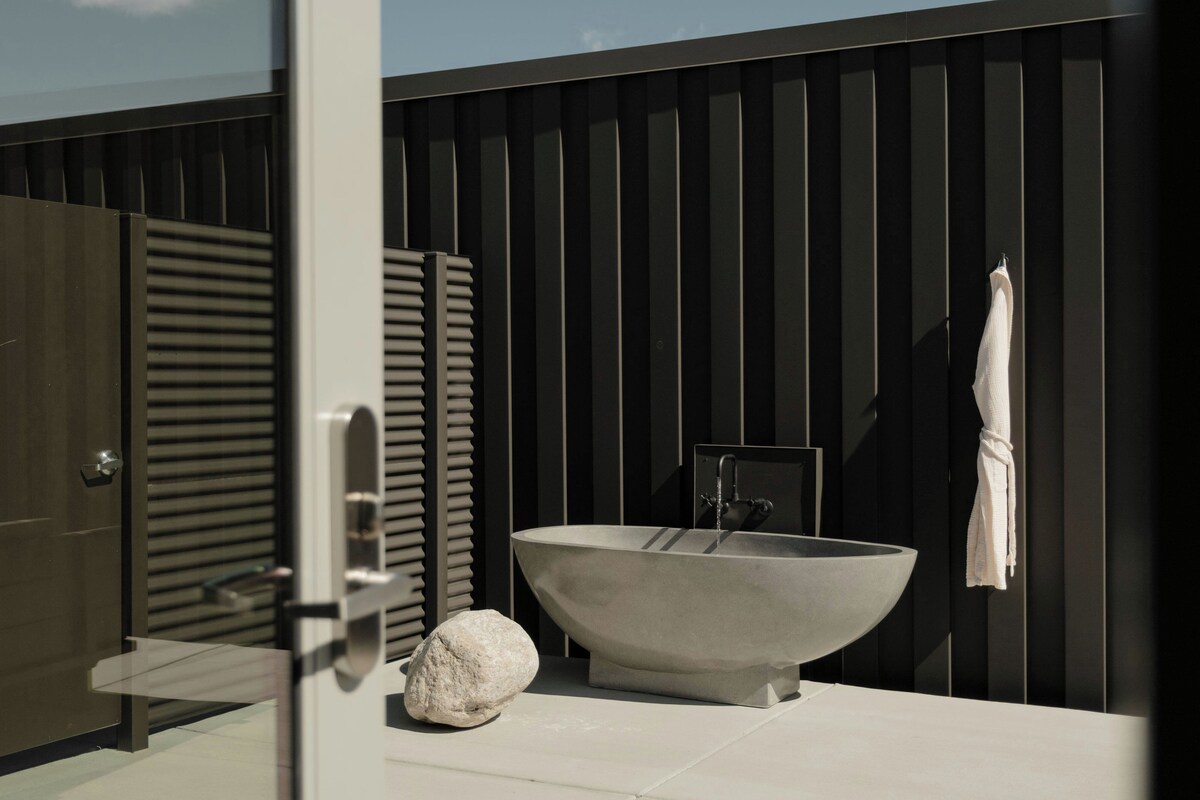Ein modernes Badezimmer mit einer großzügigen, freistehenden Badewanne, einem Handtuchhalter und einer Tür mit Griff.