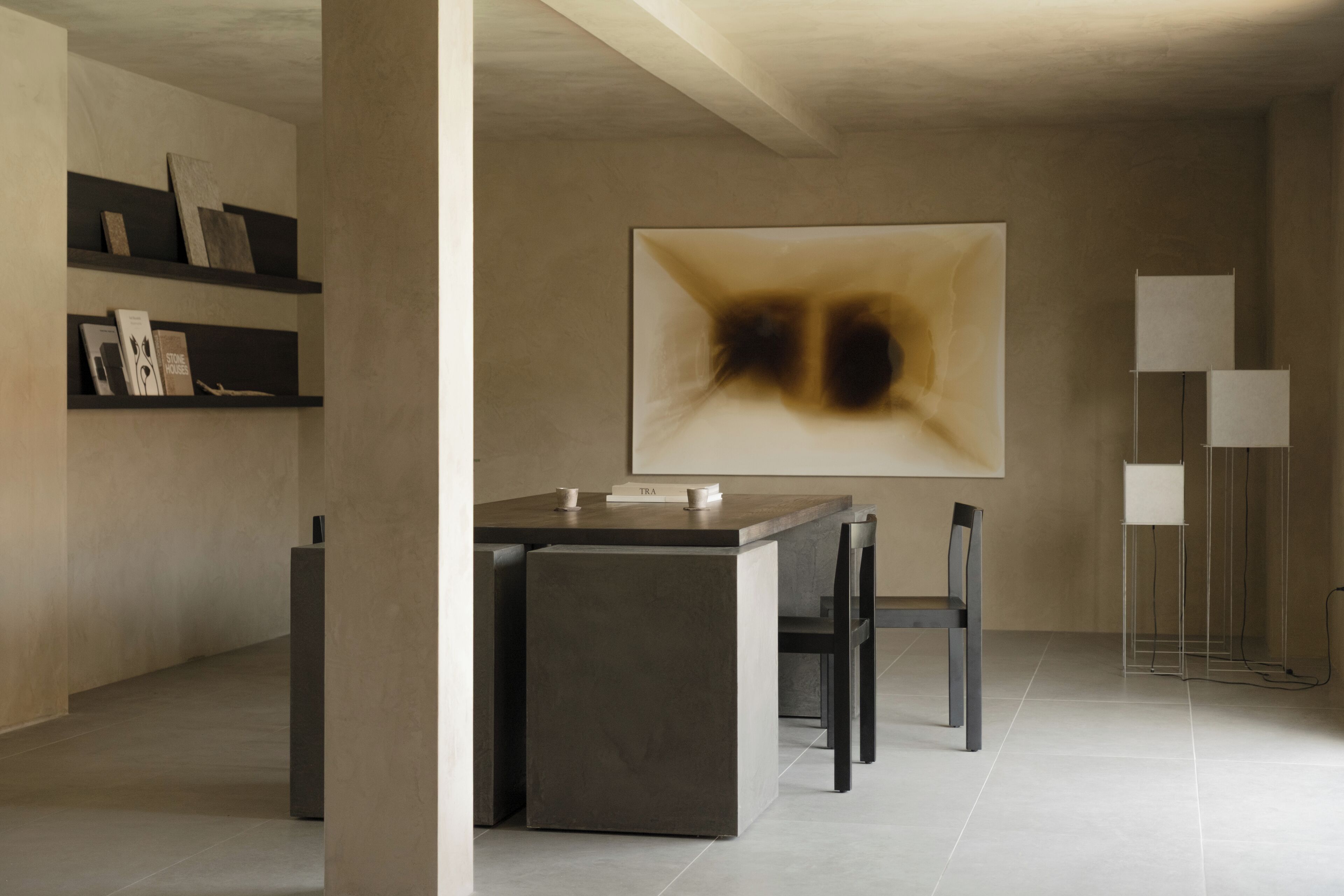 A modern interior with a minimalist dining area, a large abstract painting, and a tall floor lamp.