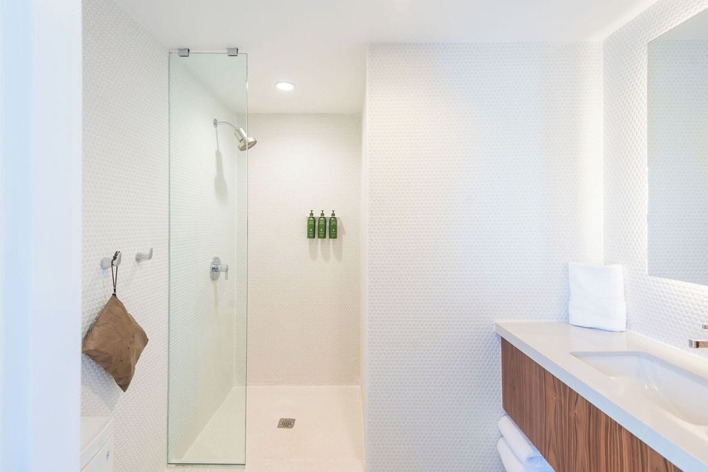 A modern bathroom with a glass shower enclosure, a wooden vanity, and a large mirror.