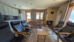 Una sala de estar con sillones de cuero, una mesa de madera y una cocina con armarios y un refrigerador.